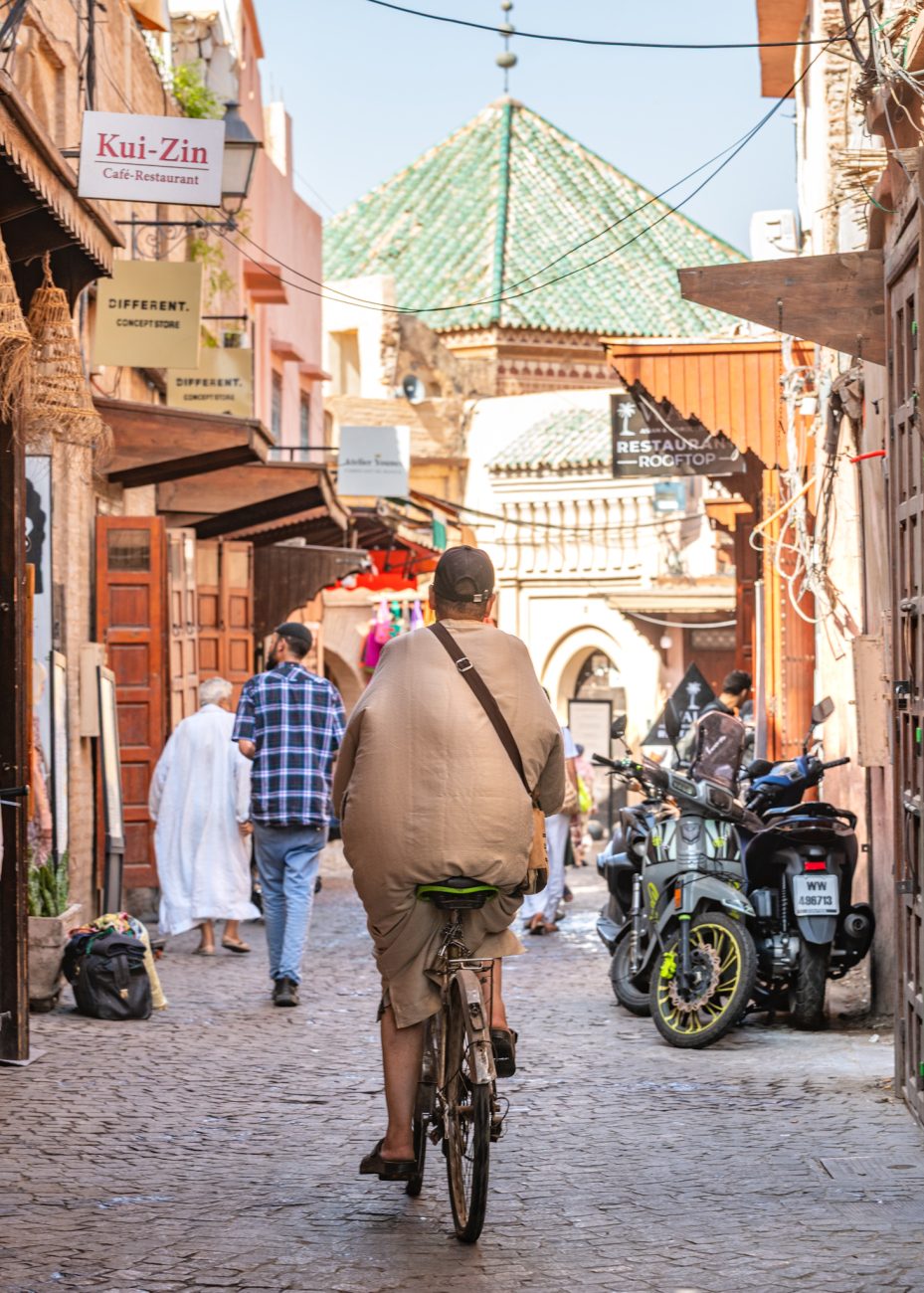 Local man riding a bike through the busy souk streets of the Marrakesh Medina
